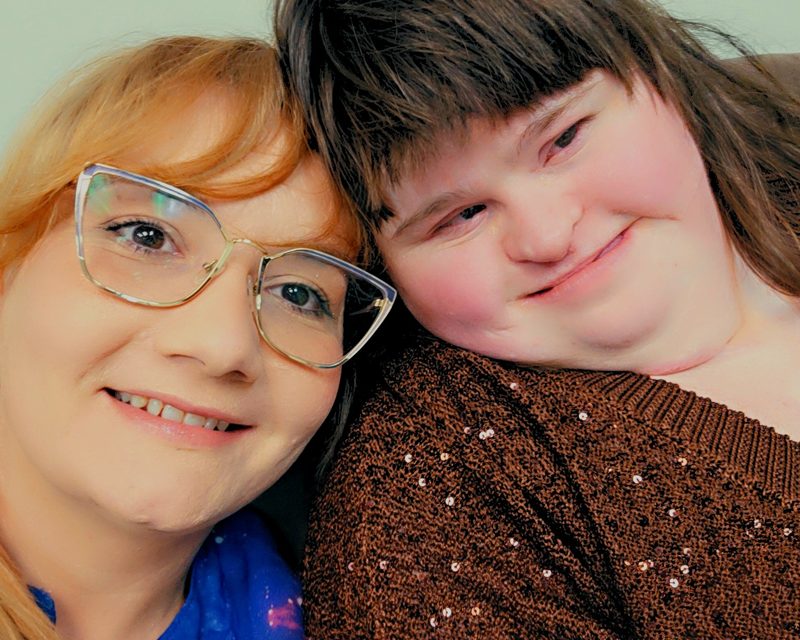 Oina and her sister Emily, smiling, cheek to cheek